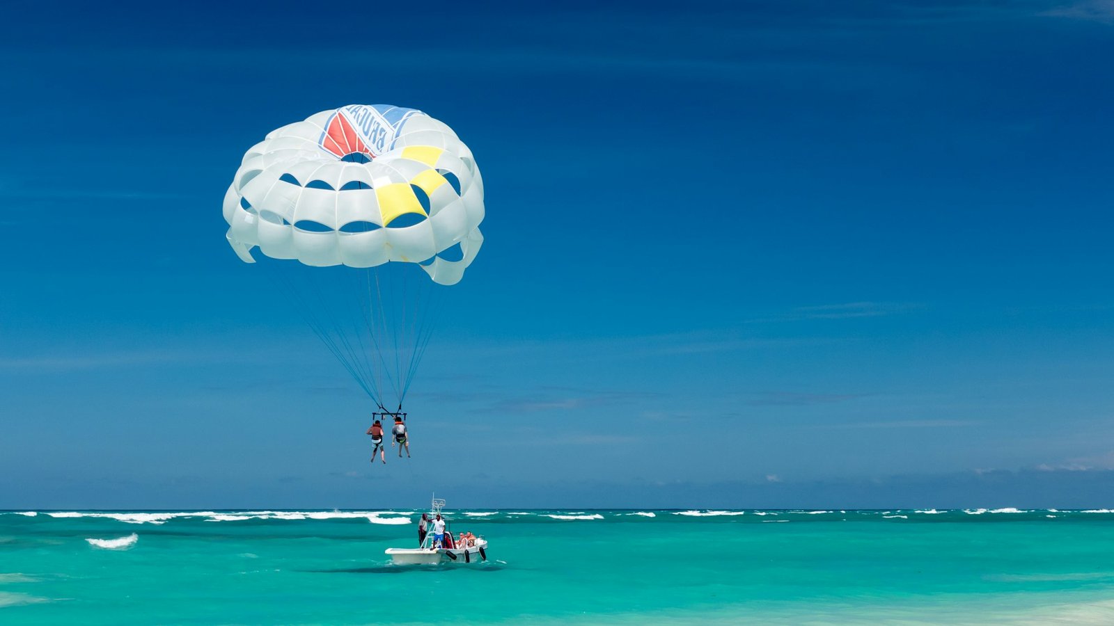 Tandem parasailing above a turquoise beach