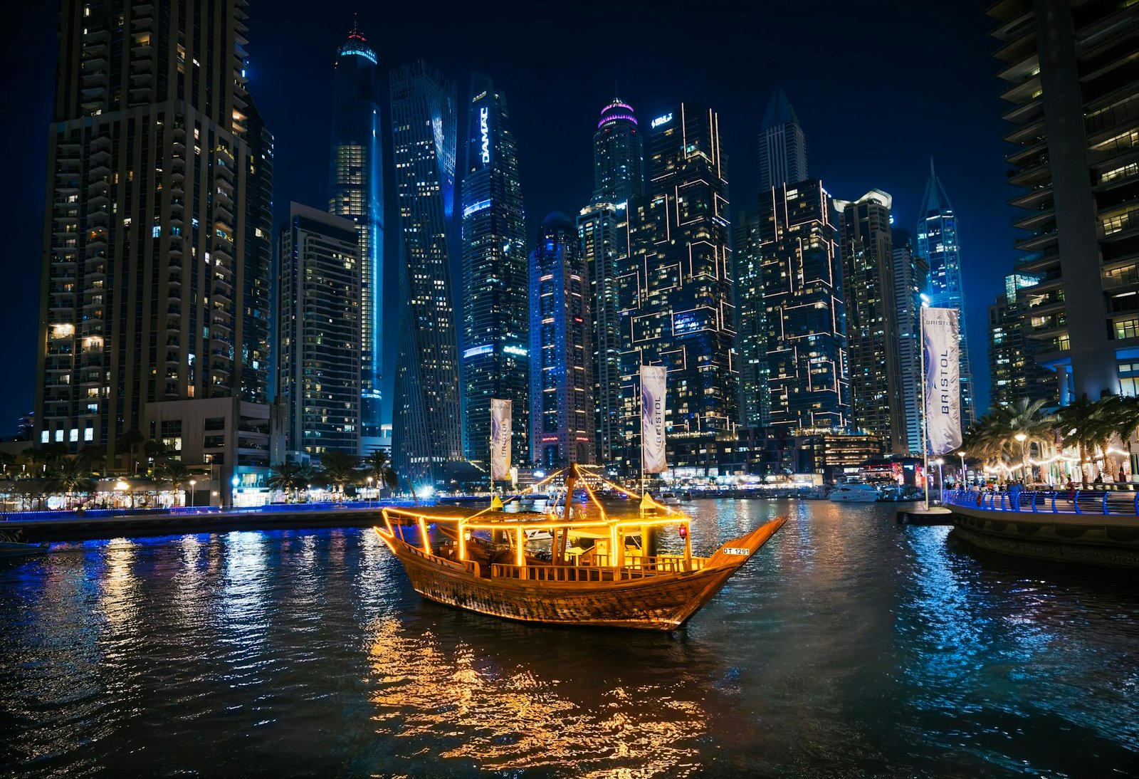 Illuminated dinner cruise boat sailing through Dubai Marina at night